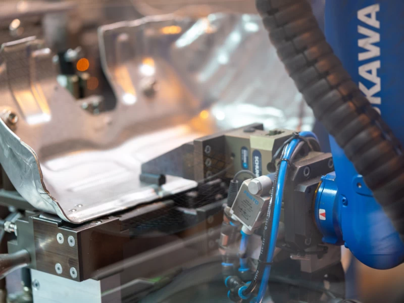 Industrieroboter bearbeitet Automobil-Metallteil in moderner Produktionsanlage bei J&S Automotive Technology